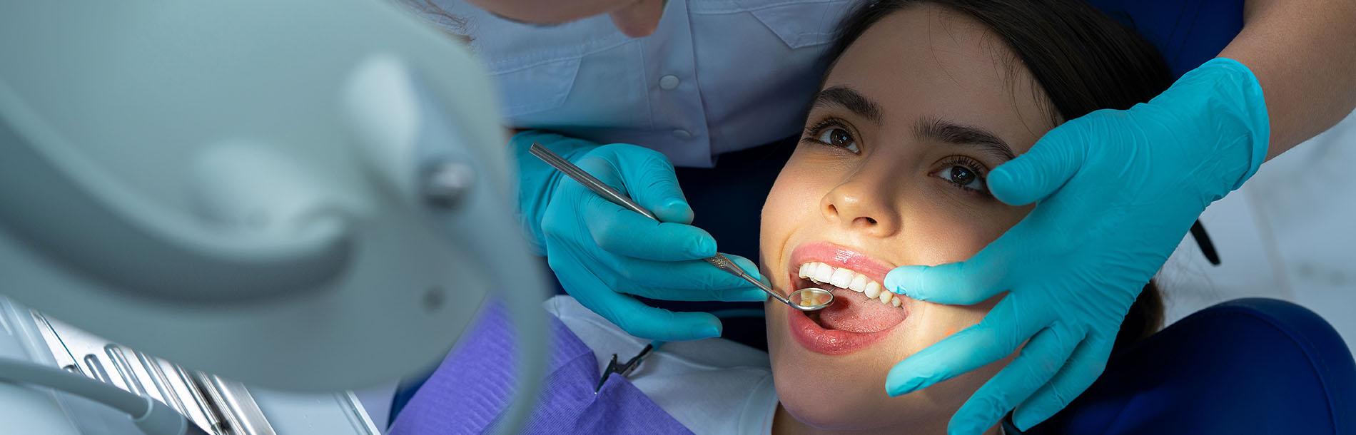 A woman receiving dental care with a medical professional, while seated in a dental chair.