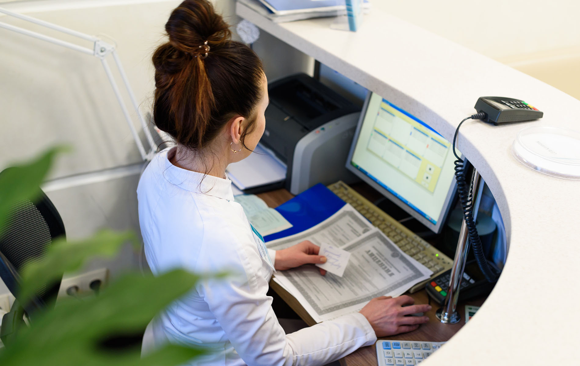 Woman seated at a desk working on a computer in an office setting.