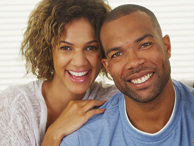 A man and woman posing together with smiles, sharing an intimate moment.