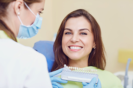 The image depicts a dental professional assisting a patient during a dental appointment.